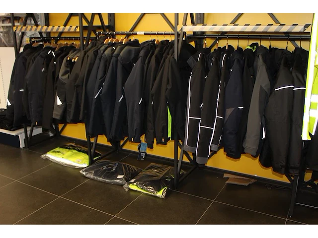 40 werkjassen en bodywarmers op rek in diverse maten merken en uitvoeringen aan en onder drie rekken. - afbeelding 1 van  2