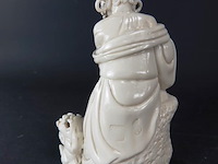 Dehua figurine bezig met dressuur fu dog zittend op een rots, blanc de chine 19/20e eeuw met blindmerk - afbeelding 3 van  5
