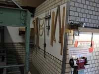 Diverse meetinstrumenten waaronder passer, linialen en blokhaken aan wand. - afbeelding 1 van  3