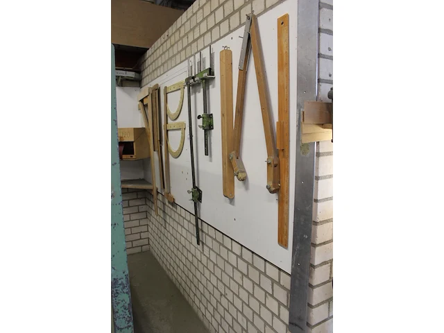 Diverse meetinstrumenten waaronder passer, linialen en blokhaken aan wand. - afbeelding 2 van  3