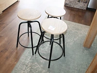 Drie in hoogte verstelbare metalen krukjes met houten zitting met doorsnede 32 cm.