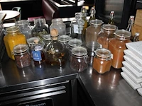 Glazen flessen en weckpotten gevuld met diverse specerijen en oliën. - afbeelding 1 van  2