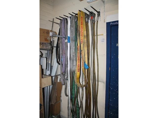 Grote hoeveelheid hijsbanden, staalkabels en ogen aan wand. - afbeelding 2 van  3