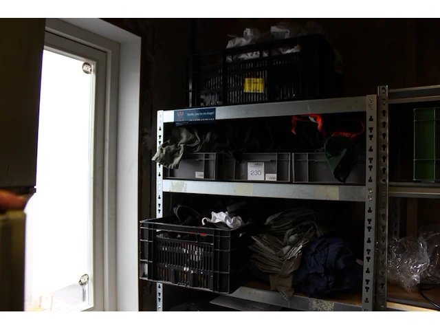 Grote hoeveelheid kleding en schoenen, waaronder blouses, t-shirts, sloven en bretels op vijf schappen en a... - afbeelding 1 van  3