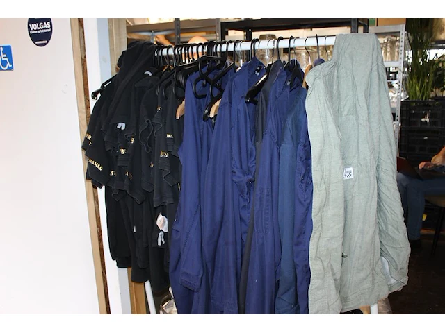 Grote hoeveelheid kleding en schoenen, waaronder blouses, t-shirts, sloven en bretels op vijf schappen en a... - afbeelding 2 van  3