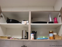 Inhoud keukenkasten bestaande uit o.a. plastic bestek, glazen (lege) drankflessen, wegwerp bordjes - afbeelding 1 van  3