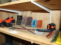 Klusproducten waaronder bitjes, handschoenen en rolmaten op schap. - afbeelding 1 van  2