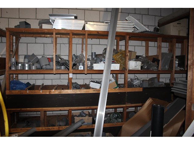Pvc koppelstukken, beugels, uitlopen, bochten, etc. in houten stelling. - afbeelding 1 van  5