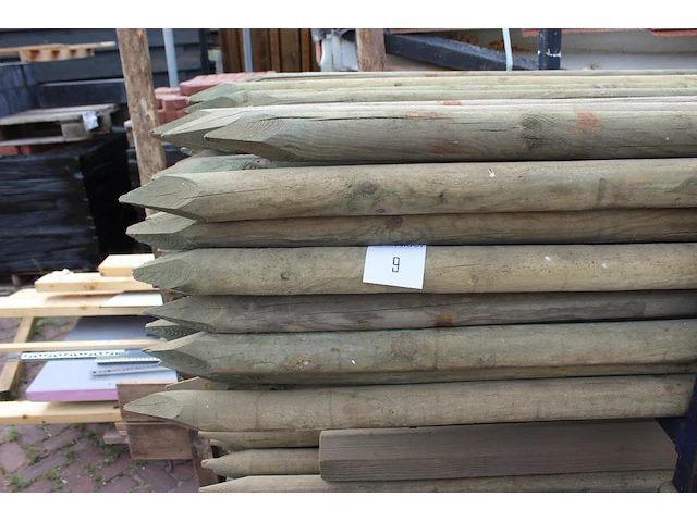 Ruim 70 boompalen in metalen bok. lengte 250 cm. doorsnede 55 mm. let op: exclusief bok. - afbeelding 2 van  3