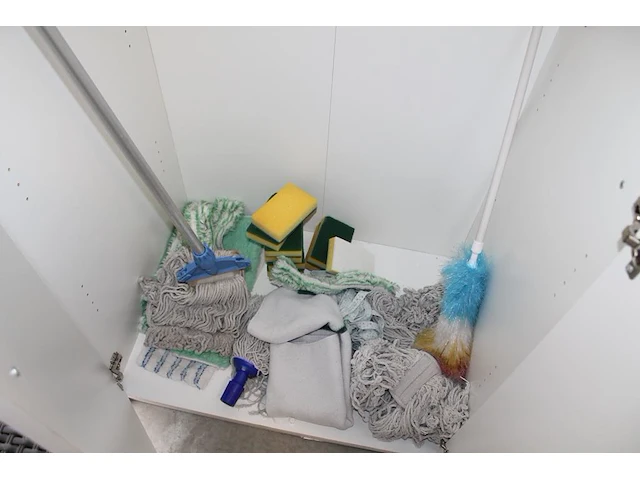 Schoonmaakproducten waaronder theedoeken, schuursponsen en moppen in kast. - afbeelding 1 van  4