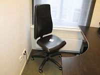 Verrijdbare, met zwart kunstleder beklede bureaustoel.