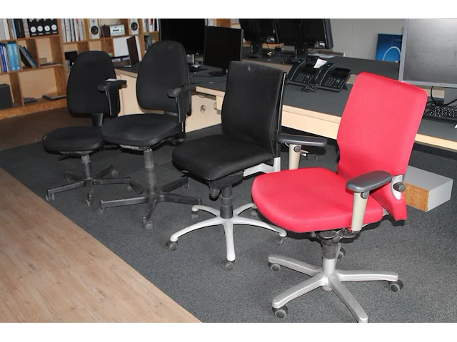 Vier verrijdbare bureaustoelen, een maal rood gestoffeerd en drie maal zwart gestoffeerd. - afbeelding 1 van  5