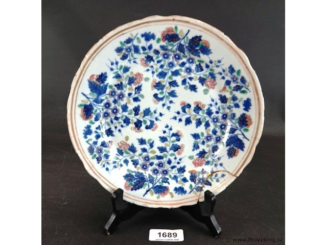 Antiek chinese porseleinen bord uit de 18e-eeuwse kangxi-periode. gedecoreerd met blauw-wit bloemmotieven en een gegolfde rand. - afbeelding 1 van  5