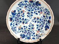Antiek chinese porseleinen bord uit de 18e-eeuwse kangxi-periode. gedecoreerd met blauw-wit bloemmotieven en een gegolfde rand. - afbeelding 1 van  5