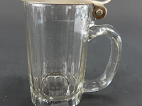 Antieke glazen bierpul met een tinnen deksel, vergelijkbaar met modellen uit duitsland rond 1900.