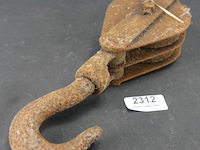 Antieke, roestige metalen katrol met een bijbehorende haak - afbeelding 1 van  5