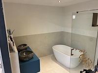 Badkamer showroom opstelling met badmeubel, vrijstaand bad en douchewand