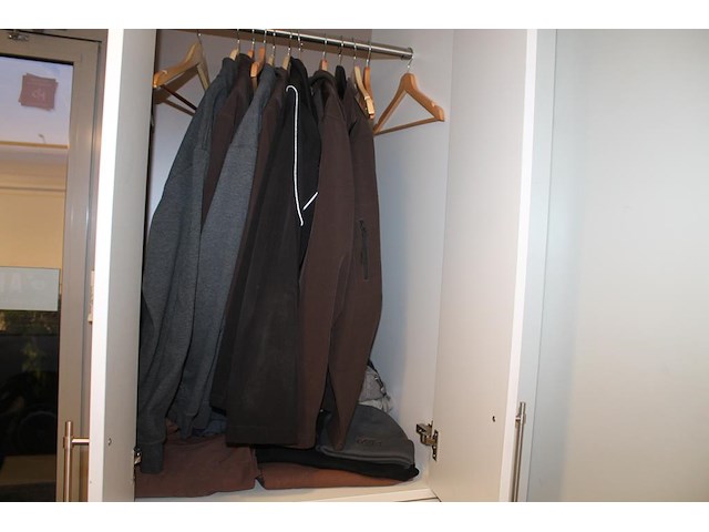 Bedrijfskleding waaronder jassen, broeken, t-shirts en mutsen in kast. - afbeelding 1 van  4