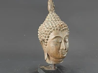 Bronzen boeddha-hoofd op een houten sokkel, uitgevoerd in traditionele thaise stijl (sukhothai-traditie) met een gevlamde ushnisha (de symbolische bult op het hoofd)