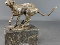 Bronzen sculptuur van een rennende poema op een marmeren voet