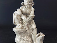 Dehua figurine bezig met dressuur fu dog zittend op een rots, blanc de chine 19/20e eeuw met blindmerk - afbeelding 1 van  5