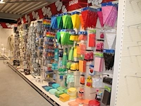 Feestartikelen/accessoires aan vier en halve wandschap w.o. ballonnen, slingers, kaarsen, buttons en tasjes...
