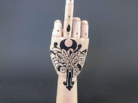 Gearticuleerde/gelede houten hand met een decoratieve, met de hand aangebrachte tatoeage-achtige illustratie van een chrysant op de handpalm en zwarte nagels - afbeelding 4 van  5