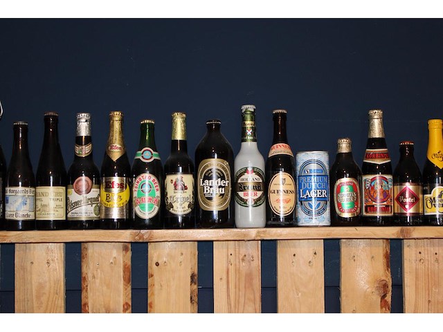 Grote hoeveelheid oude bierflessen en blikken op schap, in drie kast vakken en drie dozen. circa 150 stuks. - afbeelding 7 van  12