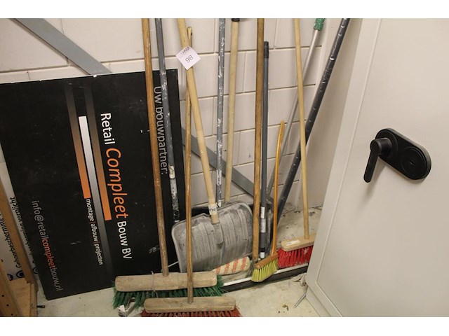 Handgereedschappen tegen de wand w.o. bezems, sneeuwscheppen, trekker etc. - afbeelding 1 van  2