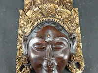Handgesneden balinees wandmasker van de rijstgodin dewi sri, prachtig gekenmerkt door de gedetailleerde, goudkleurige houtsnijwerken op de kroon
