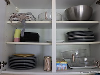 Inhoud keukenkastjes bestaande uit o.a. schoonmaakdoekjes, afwassponsjes, taartdoos, koffiebekers, snijplanken, borden & schalen - afbeelding 6 van  8