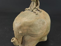 Keramieken sculptuur van een olifant met twee figuurtjes op zijn rug