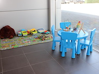 Kinderspeelhoek bestaande uit speeltafel, kleed, diverse dino's en speelgoedauto's.