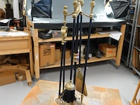 Klassieke vintage haardset met een glimmende messing standaard en zwarte stelen