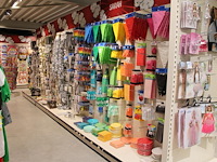Kleurige feestartikelen aan 2 1/2 wandschap w.o. slingers, ballonnen, tafelkleden, borden en bestek. - afbeelding 1 van  5