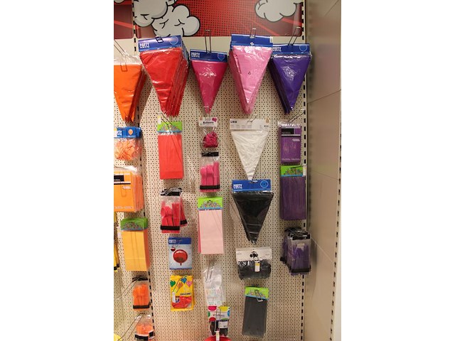 Kleurige feestartikelen aan 2 1/2 wandschap w.o. slingers, ballonnen, tafelkleden, borden en bestek. - afbeelding 2 van  5
