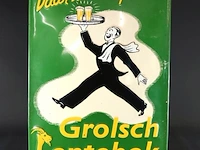 Metalen reclamebord van grolsch lentebok met een afbeelding van een dienblad dragende kelner en de tekst "daár komt hij met: grolsch lentebok"
