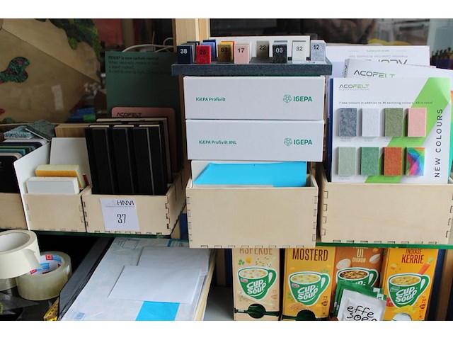 Monsters / stalen van diverse materialen w.o. vilt, kunststof en hout op glazen schappen. - afbeelding 2 van  4