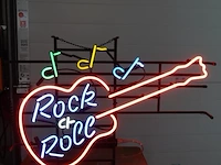 Neonreclame in de vorm van een elektrische gitaar met de tekst "rock & roll" en muzieknoten. werkend - afbeelding 2 van  7