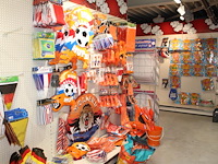 Oranje decoratie aan twee wandschappen w.o. vlaggen, borden, toeters, tassen, slingers en buttons. - afbeelding 1 van  5