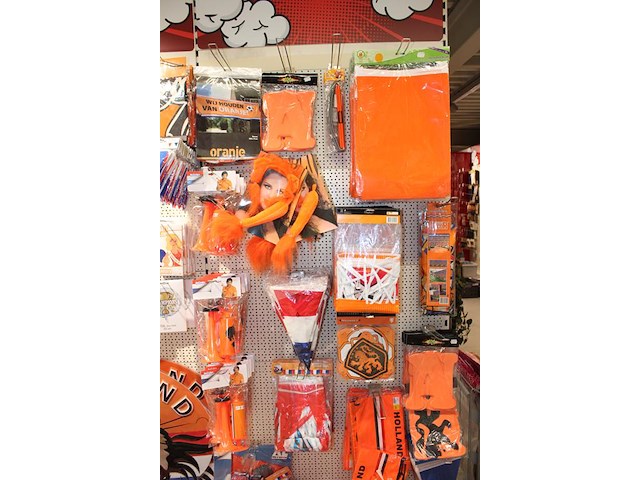 Oranje decoratie aan twee wandschappen w.o. vlaggen, borden, toeters, tassen, slingers en buttons. - afbeelding 2 van  5