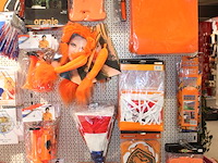 Oranje decoratie aan twee wandschappen w.o. vlaggen, borden, toeters, tassen, slingers en buttons. - afbeelding 2 van  5