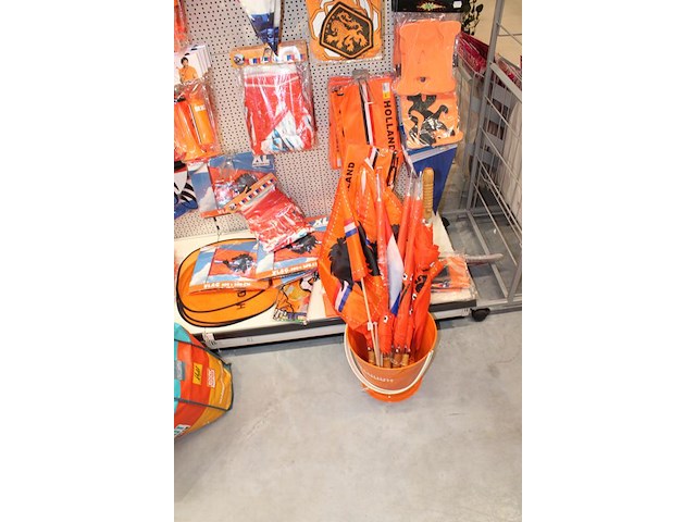 Oranje decoratie aan twee wandschappen w.o. vlaggen, borden, toeters, tassen, slingers en buttons. - afbeelding 3 van  5