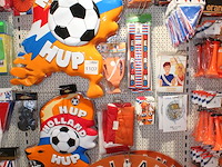 Oranje decoratie aan twee wandschappen w.o. vlaggen, borden, toeters, tassen, slingers en buttons. - afbeelding 4 van  5