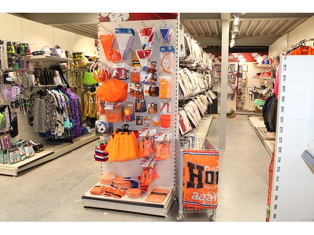 Oranje producten op kopstelling en in winkelmand w.o. vlaggen, caps, mutsen, toeters, servies en brillen. - afbeelding 1 van  2