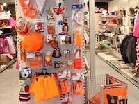 Oranje producten op kopstelling en in winkelmand w.o. vlaggen, caps, mutsen, toeters, servies en brillen. - afbeelding 2 van  2