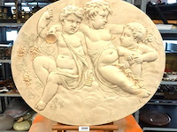 Ovale stenen neoklassieke wandplaques met putti of cherubijntjes en druiventrossen (een bacchanaalse scène), en is vermoedelijk geproduceerd in de 19de eeuw of begin 20e eeuw