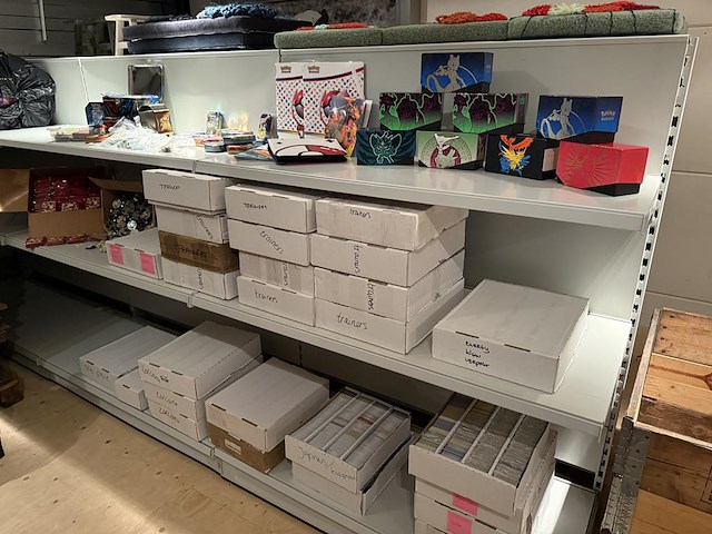 Pokemon producten op drie stellingschappen w.o. pokemon kaarten, pins pokemon blikken, pokemon verzamelmapp... onderdeel van combinatiekavel kavels p001 t/m p051 combinatiekavel - afbeelding 8 van  15