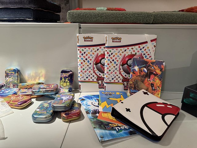 Pokemon producten op drie stellingschappen w.o. pokemon kaarten, pins pokemon blikken, pokemon verzamelmapp... onderdeel van combinatiekavel kavels p001 t/m p051 combinatiekavel - afbeelding 10 van  15