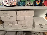 Pokemon producten op drie stellingschappen w.o. pokemon kaarten, pins pokemon blikken, pokemon verzamelmapp... onderdeel van combinatiekavel kavels p001 t/m p051 combinatiekavel - afbeelding 14 van  15